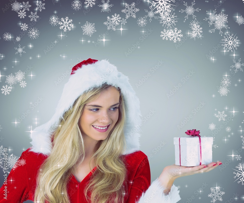 Composite image of pretty girl in santa outfit holding gift Composite image of pretty girl in santa outfit holding gift