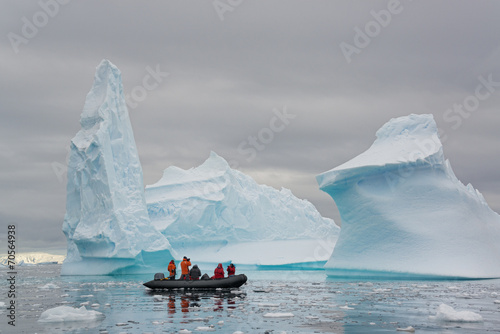 People in inflatible zodiac rib boats passing icebergs at Antarctic Peninsula. photo