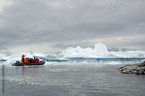 People in small inflatible zodiac rib boats passing icebergs and ice floes on the calm water around small islands of the Antarctic. photo