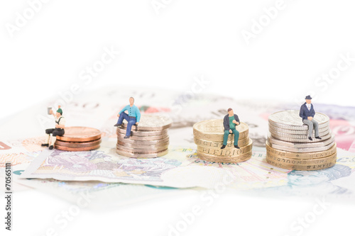 Miniature people sitting on coins close-up