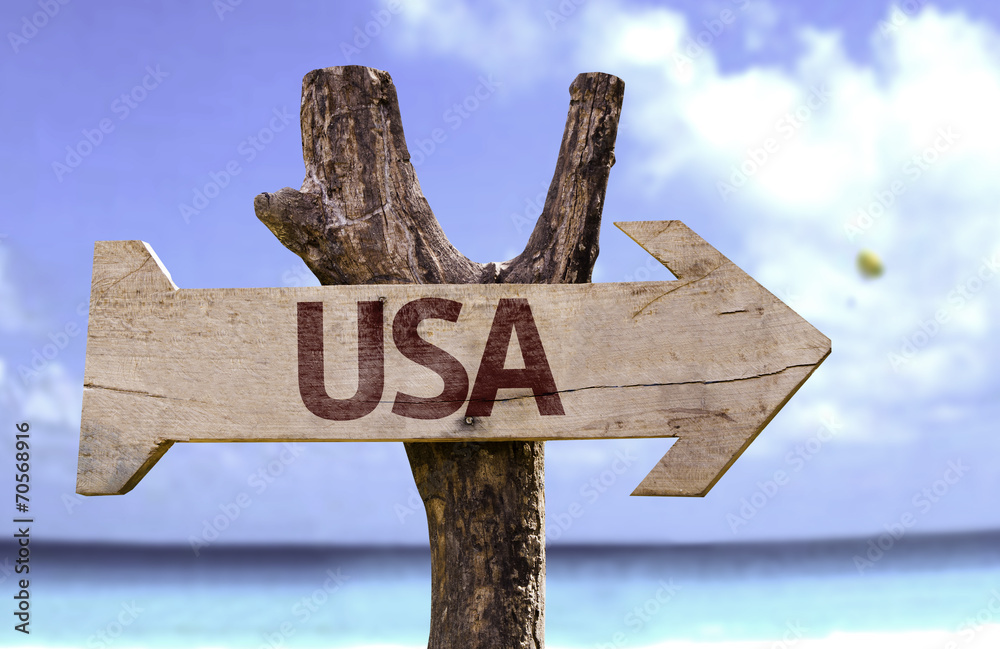 USA wooden sign with a beach on background