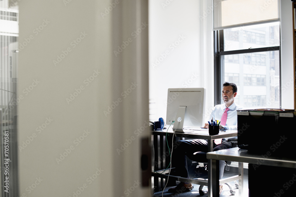 A man seated in an office using a computer. A man seated in an office using a computer.