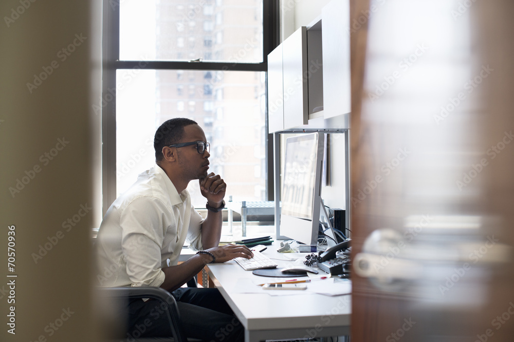 A man working in an office seated at a desk. Looking at a computer screen. A man working in an office seated at a desk. Looking at a computer screen.