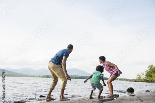 A family, mother, father and son playing on the shores of a lake. photo