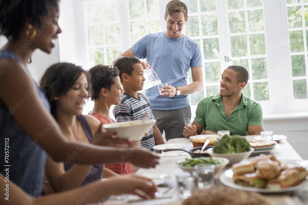 A family gathering; men; women and children around a dining table sharing a meal. A family gathering; men; women and children around a dining table sharing a meal.