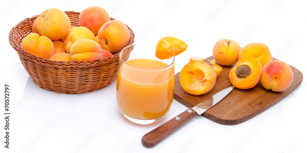Glass of apricot juice with a basket of apricots and sliced apri Glass of apricot juice with a basket of apricots and sliced apri
