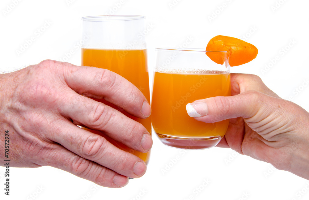 Woman's and man's hand making a toast with glasses of apricot ju Woman's and man's hand making a toast with glasses of apricot ju