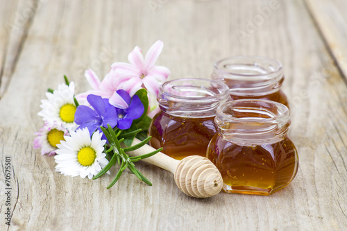 Honey in jars  flowers and honey dipper on wooden background