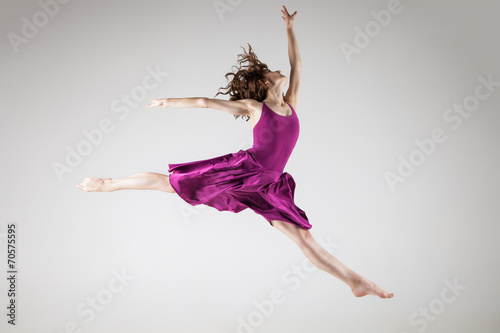 Young ballet dancer wearing purple dress over grey
