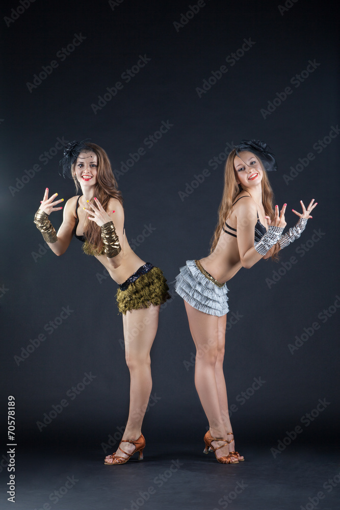 two cabaret dancers in bright costumes over dark
