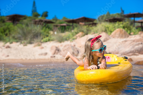 Little cute girl enjoying swimming on yellow kayak in the clear