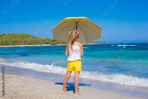 Rear view of little girl with big umbrella walking on tropical