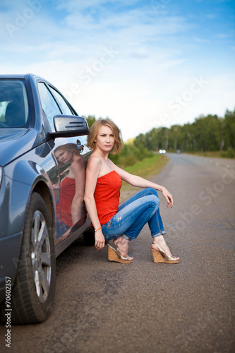 Девушка сидит на дороге летом у автомобиля © dina777
