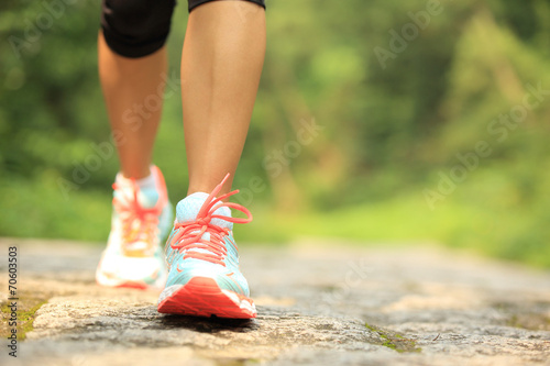young fitness woman legs walking on forest trail photo