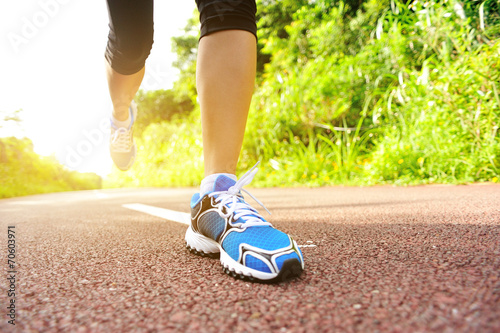 young fitness woman legs running on forest trail