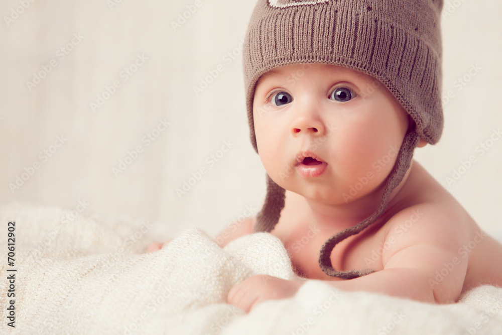 Baby lying on a soft bed cover with cap Baby lying on a soft bed cover with cap
