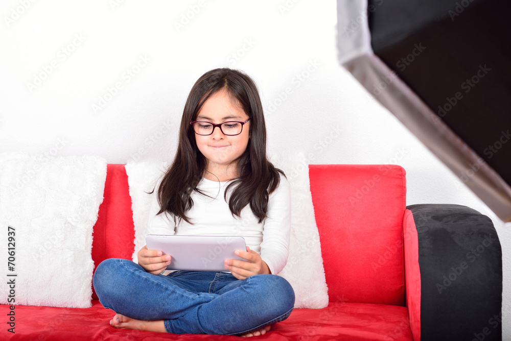 Little cute schoolgirl with a Tablet PC in a photo studio