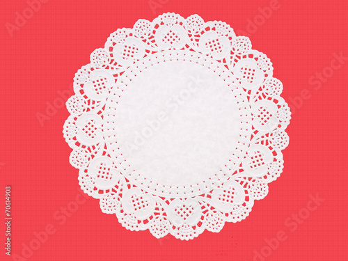 Fancy paper doily, round, perforated, embossed, on textured red.