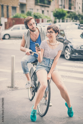 couple of friends young man and woman riding bike