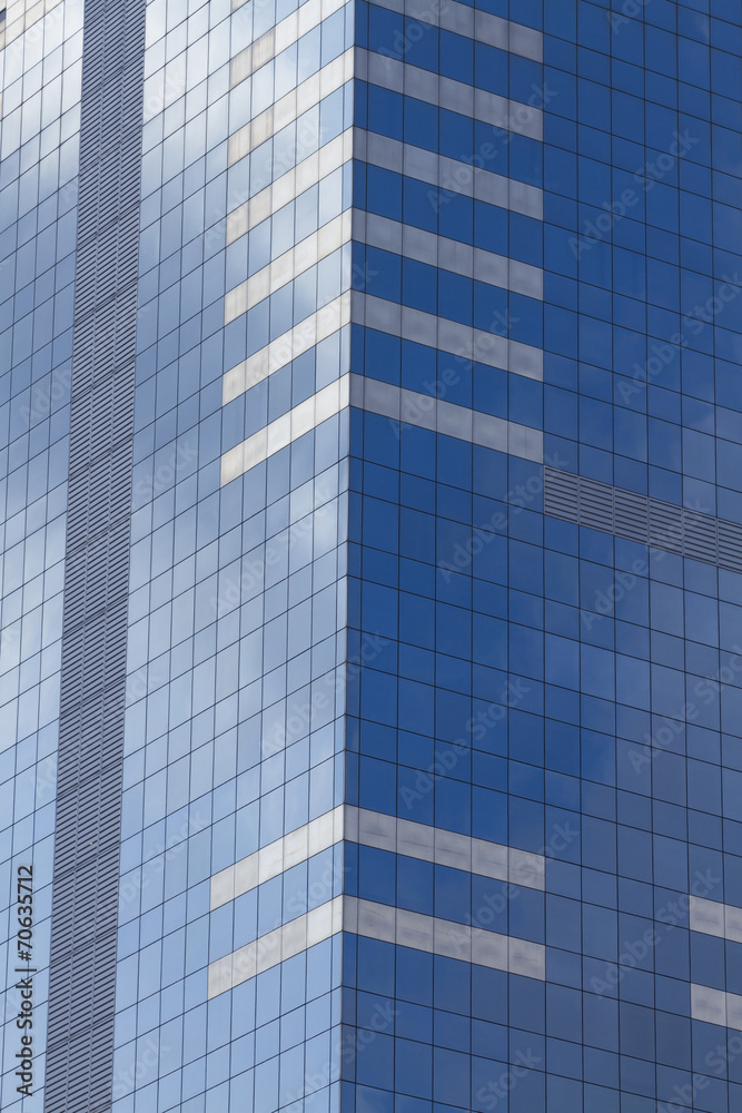 Glass skyscraper with blue sky and clouds reflected in windows. Glass skyscraper with blue sky and clouds reflected in windows.