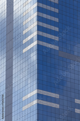 Glass skyscraper with blue sky and clouds reflected in windows.