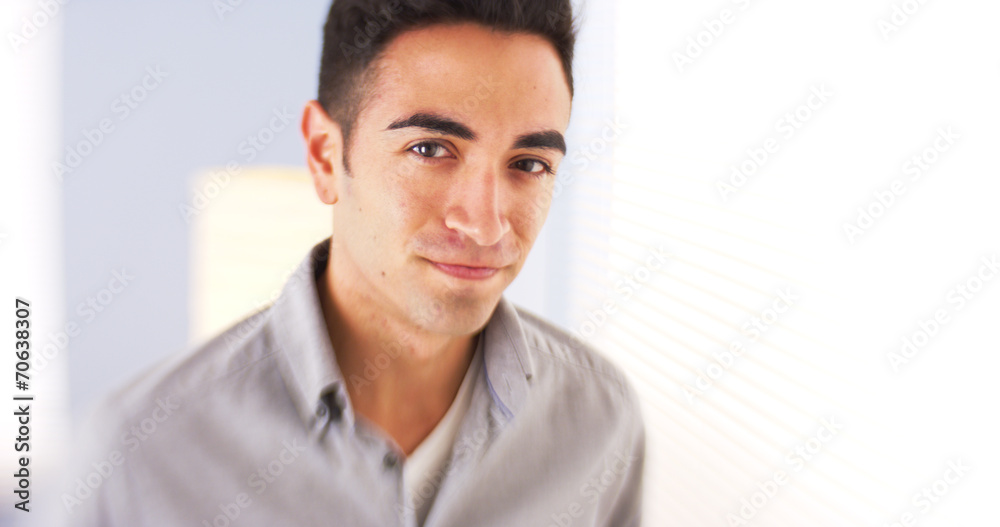 Confident Mexican man standing by window Confident Mexican man standing by window