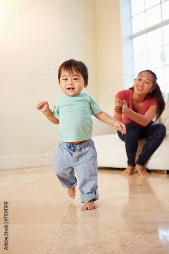 One Year Old Boy Taking First Steps With Mother