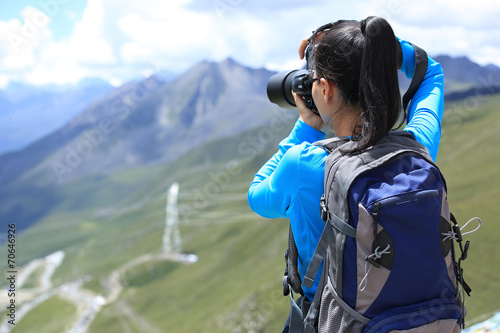 hiking woman taking photo at mountain peak in tibet,china