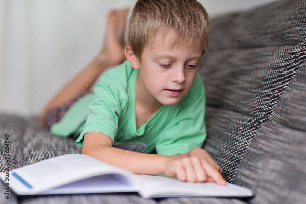 junge liegt auf dem sofa und liest ein buch junge liegt auf dem sofa und liest ein buch