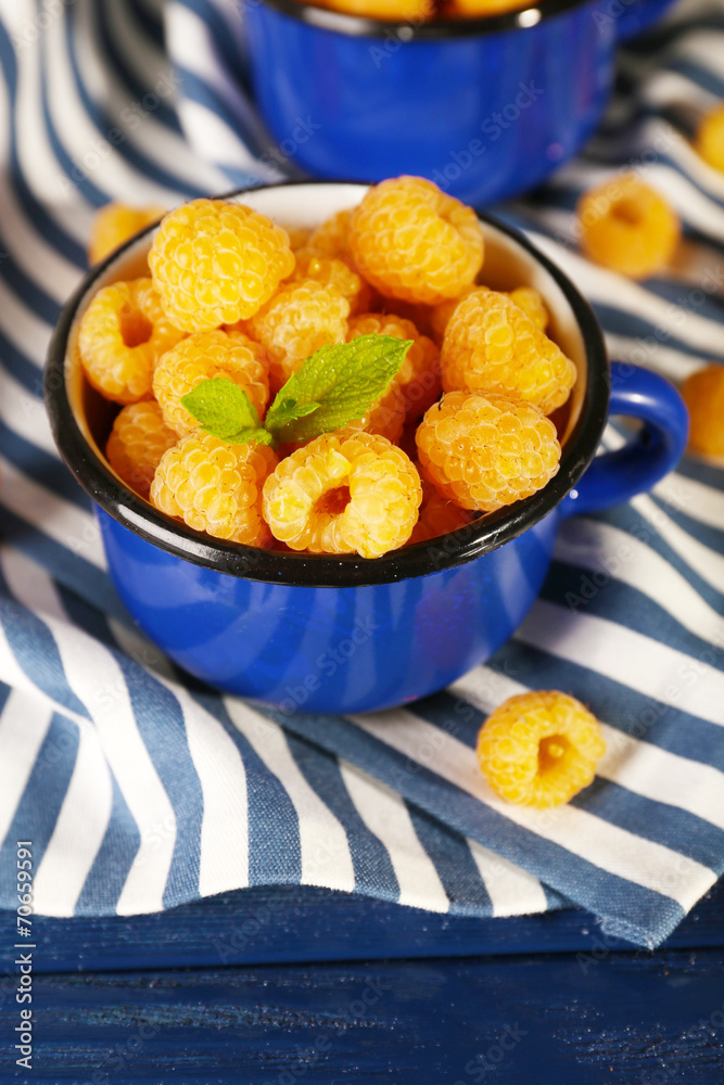 Yellow raspberries in dark blue mugs Yellow raspberries in dark blue mugs