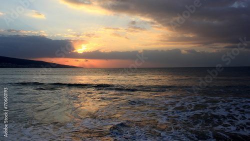 spectacular sunrise from behind the clouds on the sea shore