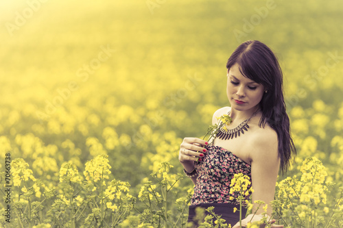 Beautiful woman in meadow of yellow flowers with glimps down