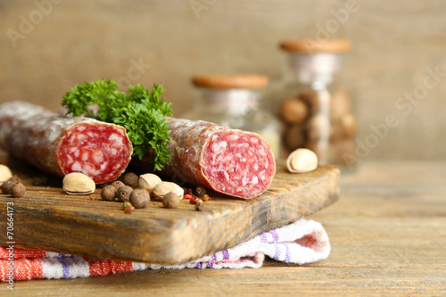 Italian salami on wooden cutting board, on wooden background
