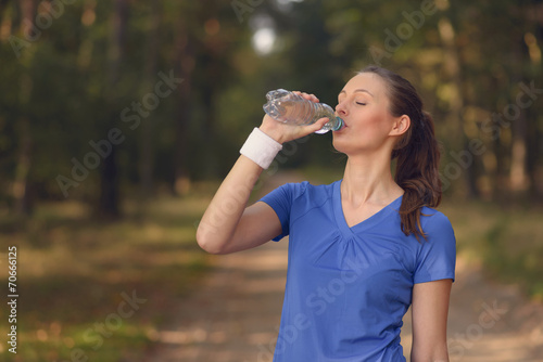 Sportliche junge Frau trinkt aus einer Wasserflasche photo