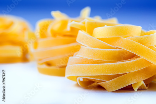 Tagliatelle pasta on white blue background.Macro concept