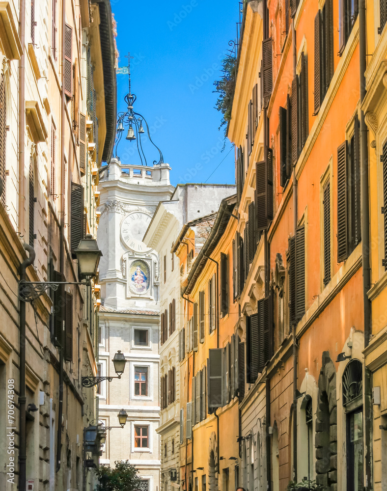 Narrow street of Rome and white church with bells