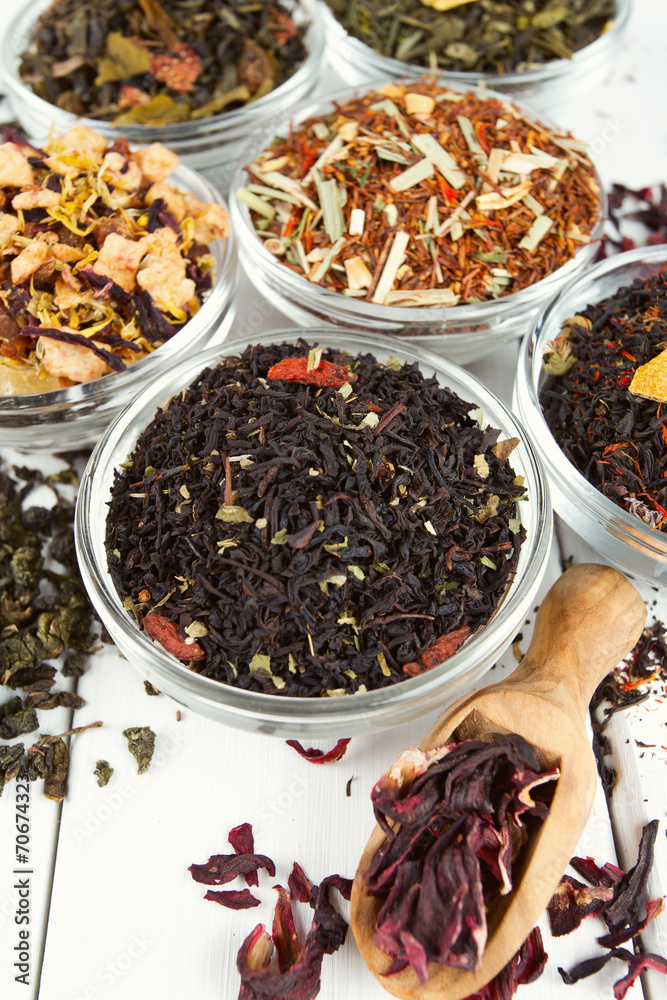 assortment of dry tea in glass bowls on wooden surface assortment of dry tea in glass bowls on wooden surface