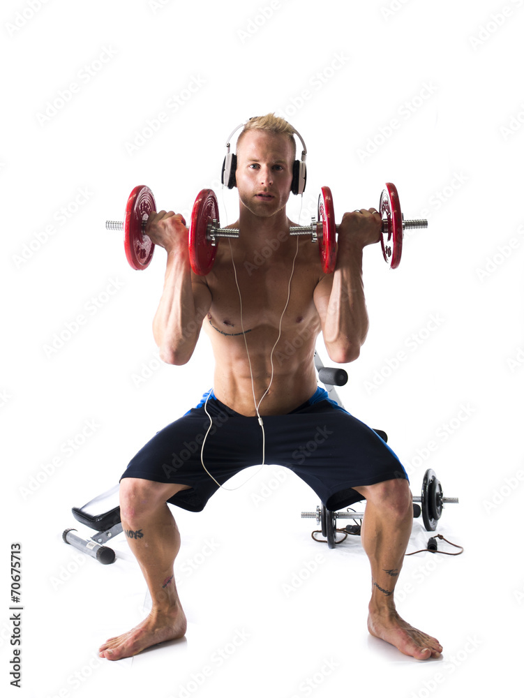 Obraz premium Man Wearing Headphones Lifting Weights in Studio