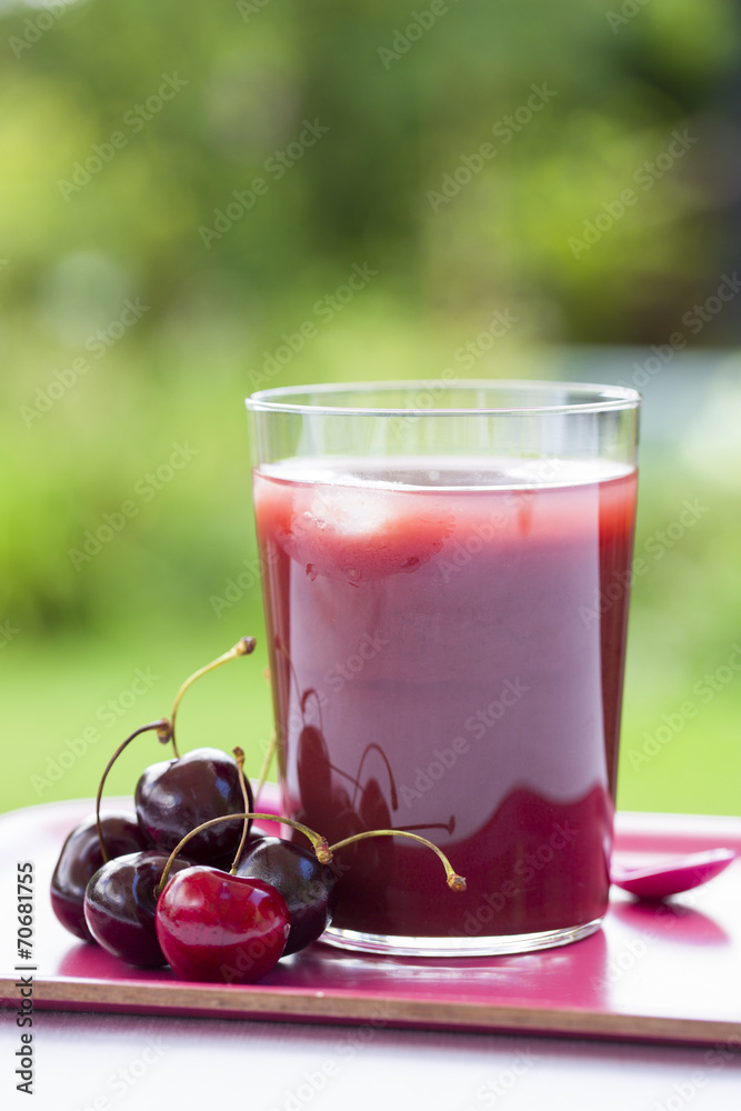 Glass of Cold cherries juice in garden Glass of Cold cherries juice in garden