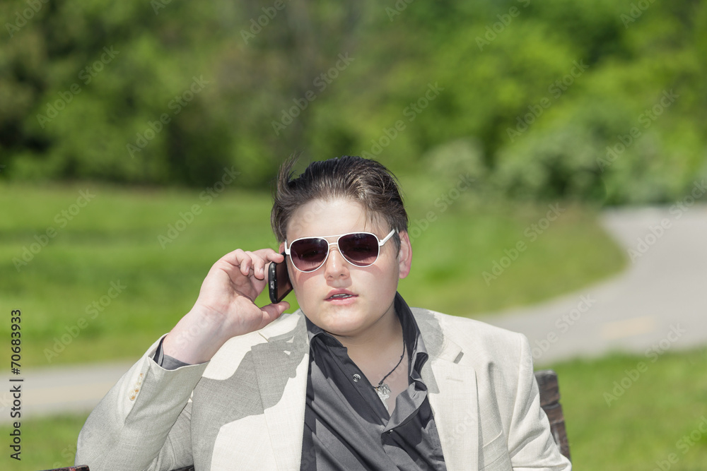 young adolescent sitting in park and talking on cellphone young adolescent sitting in park and talking on cellphone