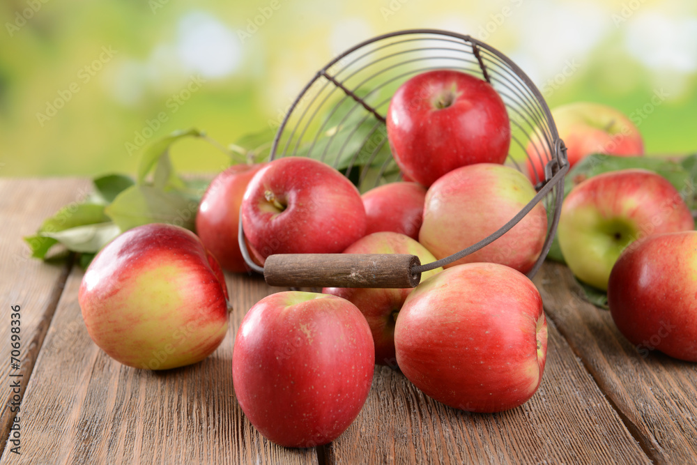 Sweet apples in wicker basket on table on bright background Sweet apples in wicker basket on table on bright background