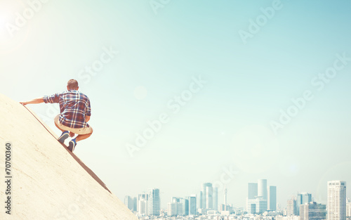 Young man sitting on a cliff and city
