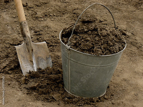 bucket full of soil with spade on dirt background