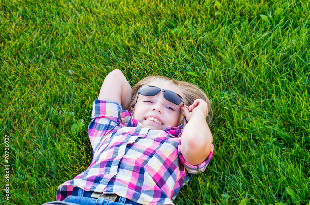 Fototapeta premium Beautiful little girl lying in fresh green grass