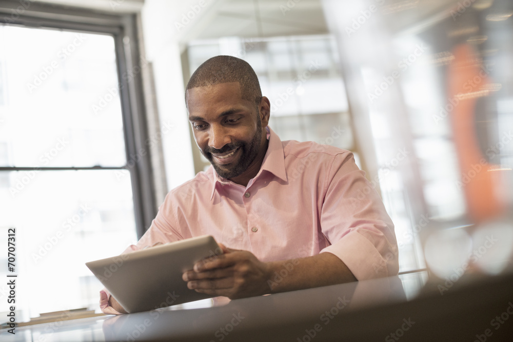 Office life. A man seated at a desk using a laptop computer. Office life. A man seated at a desk using a laptop computer.