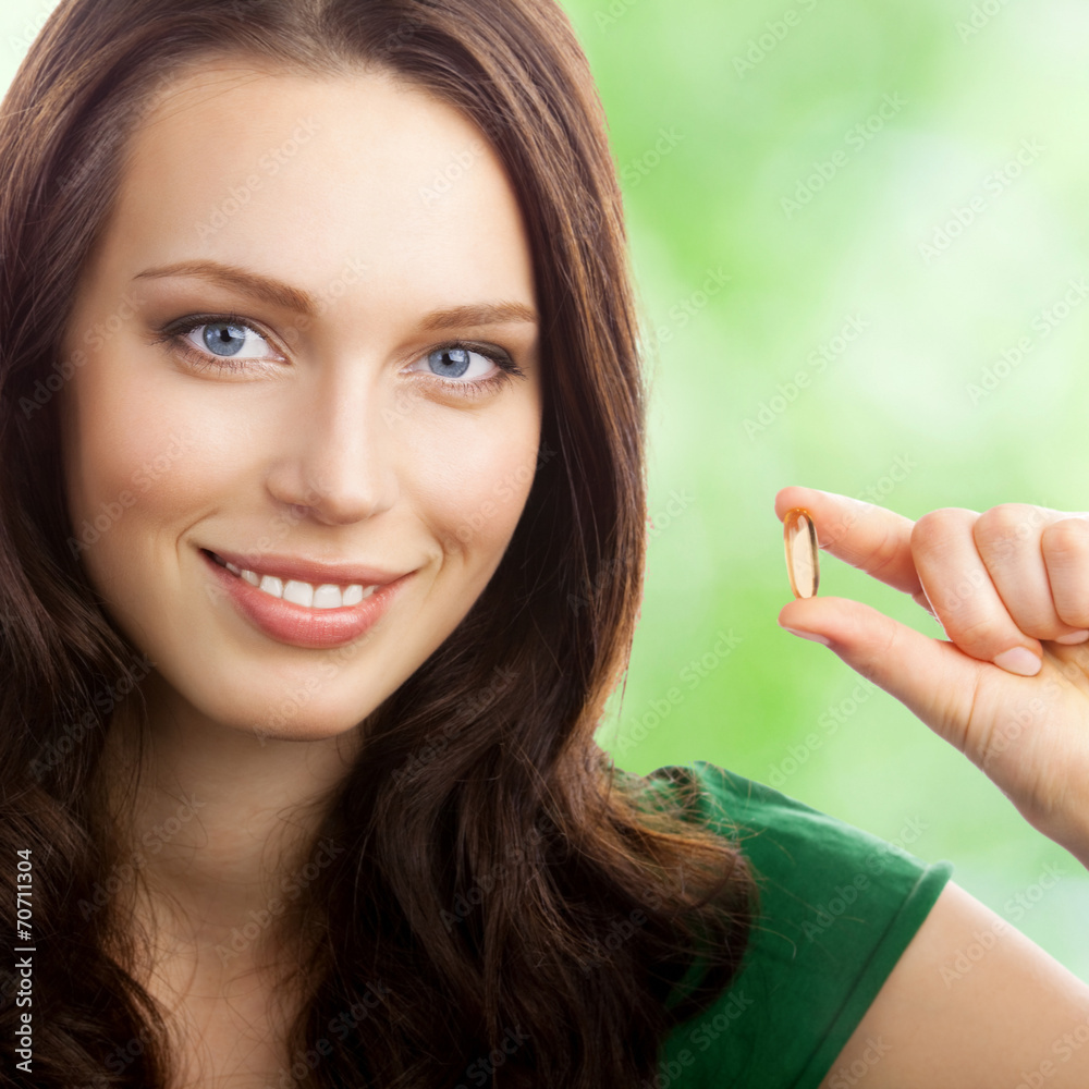 Woman with Omega 3 fish oil capsule, outdoor Woman with Omega 3 fish oil capsule, outdoor
