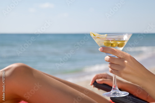 Hand of a girl with a cocktail on the beach