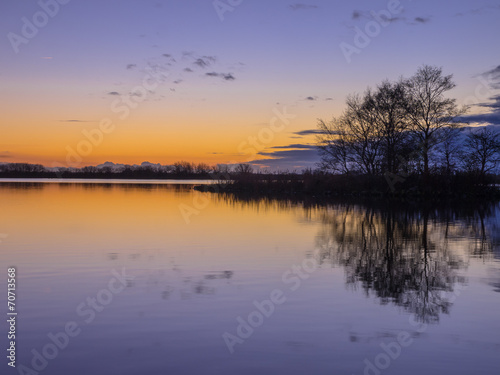 Trees and Clouds reflecting in a lake during a beautiful Sunset