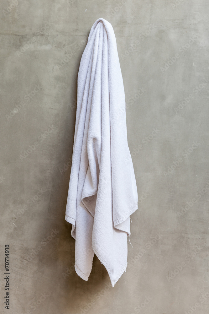 Obraz premium White towel is hanging on the exposed concrete wall in the bathr