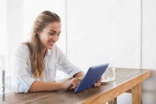 Pretty blonde having coffee while using tablet